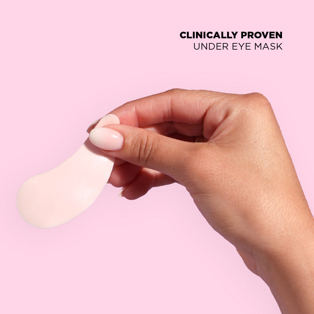 Hand holding a white under eye mask against a pink background with text 'Clinically Proven Under Eye Mask'.