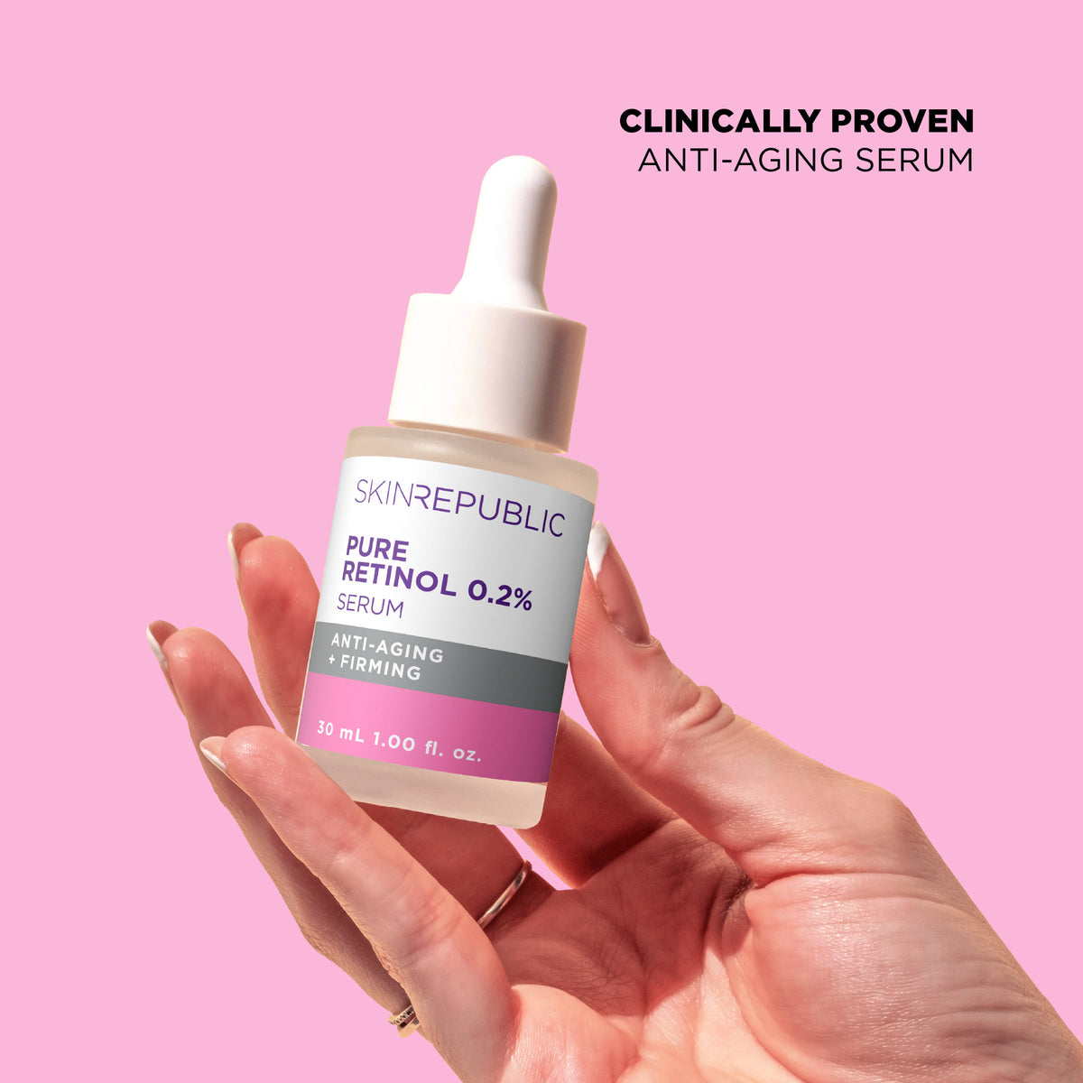Hand holding a bottle of Skin Republic Pure Retinol 0.2% serum against a pink background